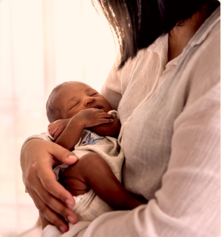 Photo of a woman holding a sleeping baby.